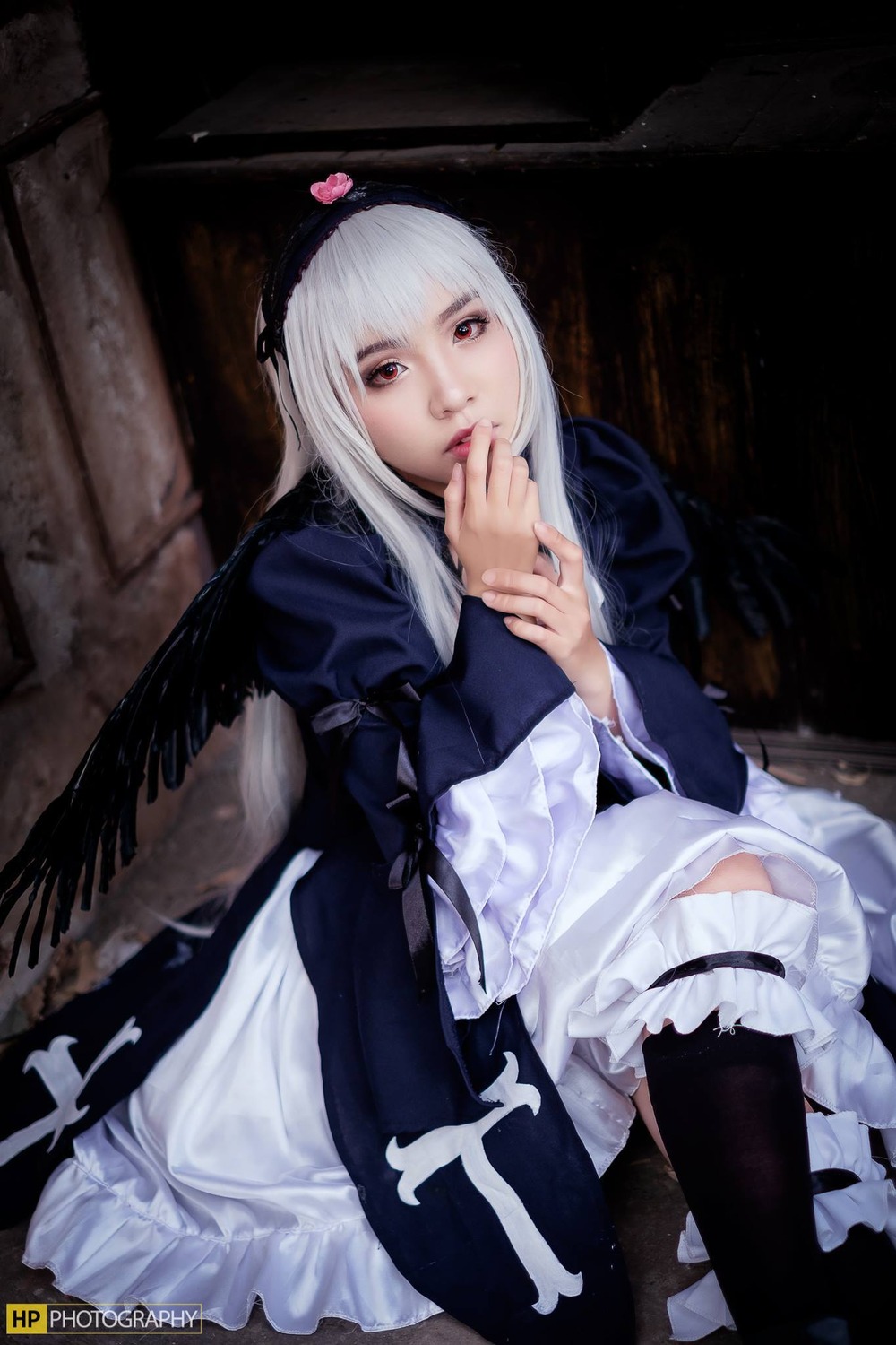 1girl black_legwear dress feathers frills hairband lips long_hair long_sleeves looking_at_viewer puffy_sleeves red_eyes sitting solo suigintou thighhighs wings