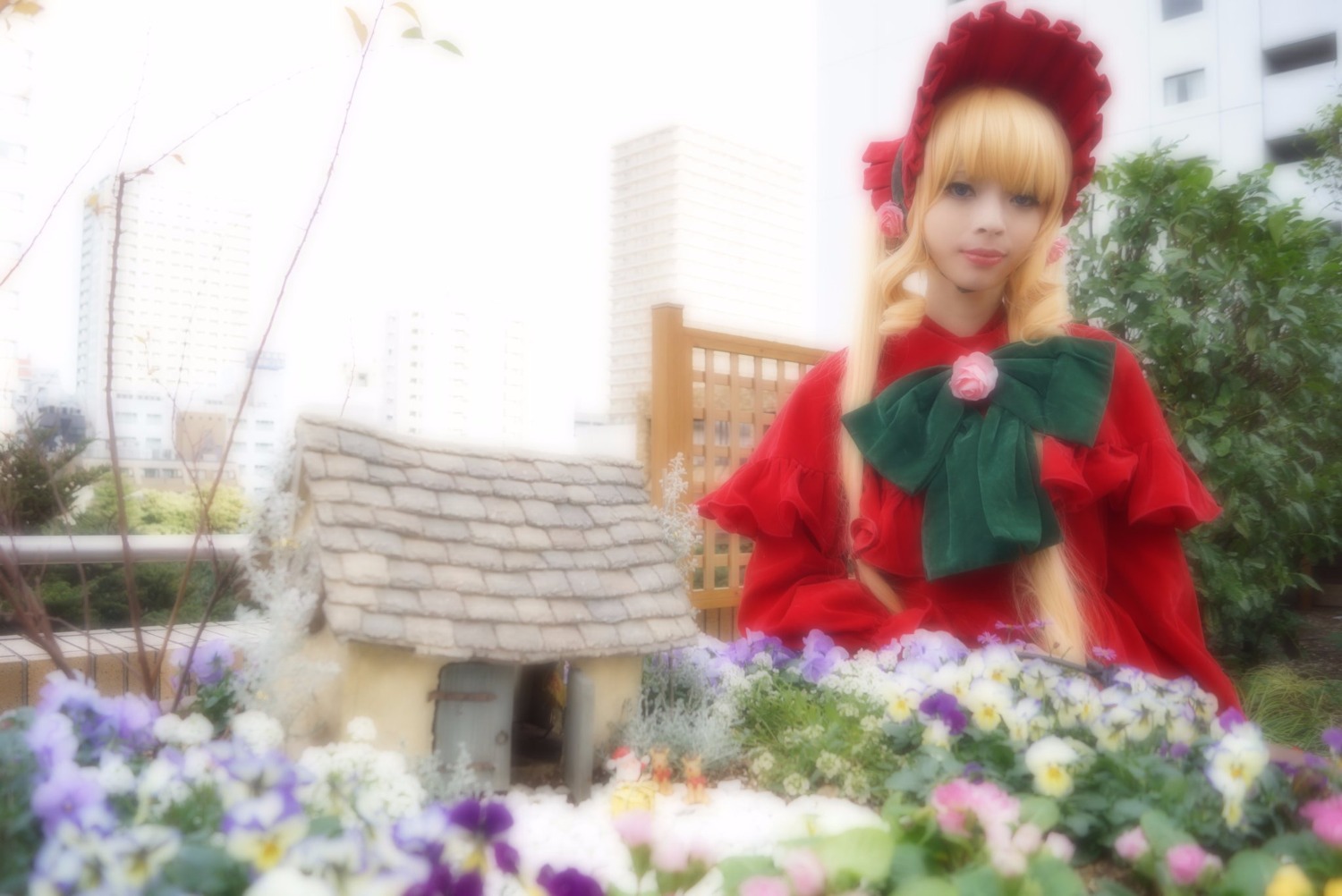 1girl blonde_hair blue_eyes blurry bonnet bow building depth_of_field dress flower green_neckwear long_hair photo shinku solo