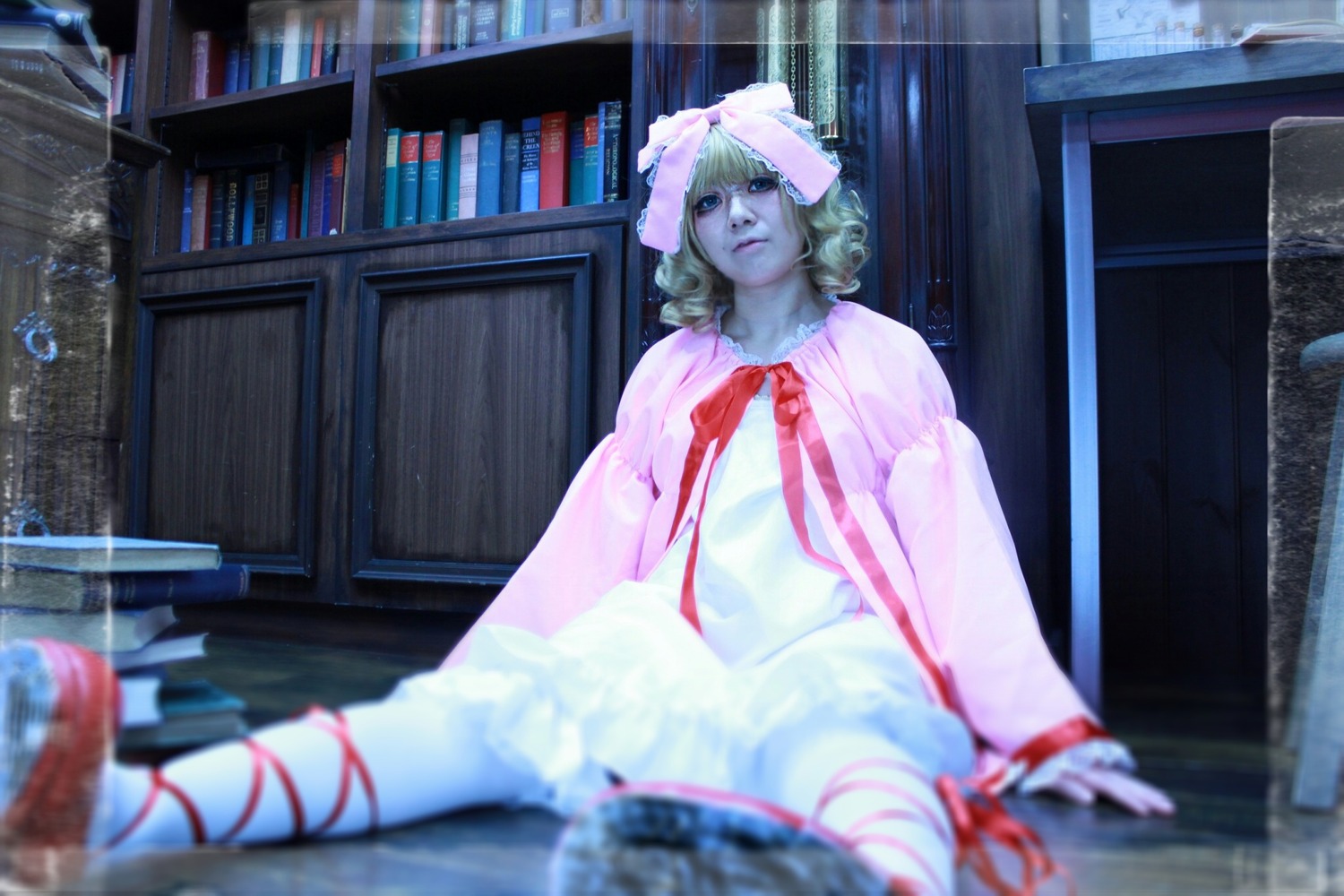blonde_hair blurry blurry_foreground bookshelf depth_of_field dress hinaichigo indoors photo ribbon sitting solo