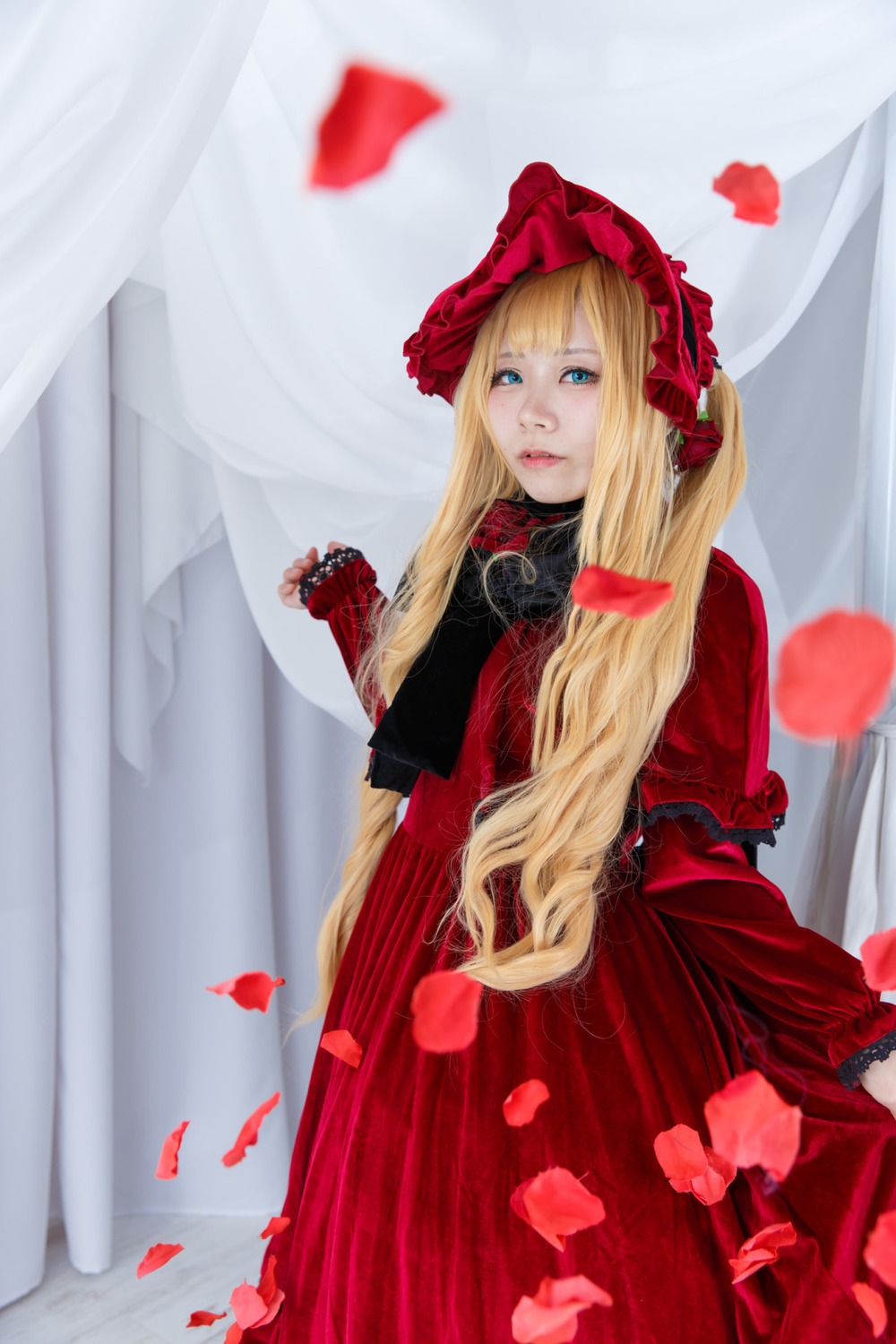 1girl blonde_hair blue_eyes blurry blurry_background blurry_foreground bonnet curtains depth_of_field dress flower lips long_hair looking_at_viewer petals red_dress rose_petals shinku solo