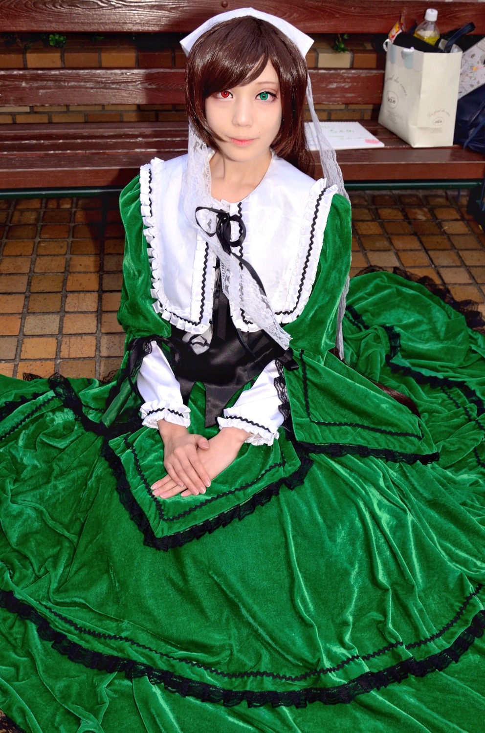 1girl brown_hair dress frills green_dress green_eyes heterochromia long_sleeves looking_at_viewer red_eyes short_hair sitting smile solo suiseiseki