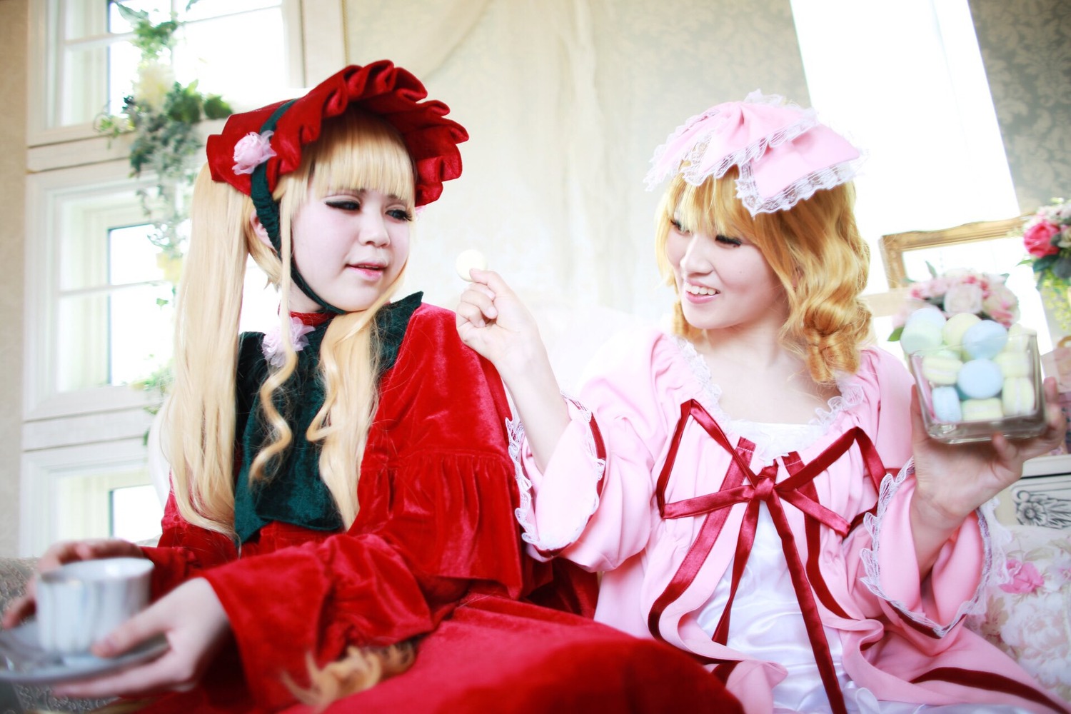 2girls blonde_hair blurry blurry_background blurry_foreground closed_eyes cup curtains depth_of_field flower hat indoors long_hair looking_at_another multiple_cosplay multiple_girls realistic shinku sitting table tagme teacup window