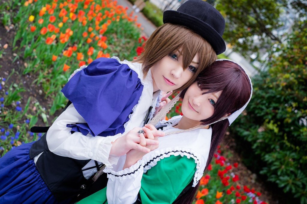 2girls 3d blonde_hair blue_eyes blurry brown_hair bush capelet depth_of_field dress flower flower_field garden hat holding_hands lips long_hair multiple_cosplay multiple_girls outdoors short_hair siblings sisters smile tagme wisteria