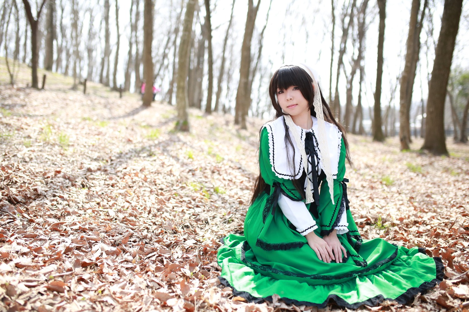 1girl bangs black_hair blunt_bangs blurry dress green_dress long_hair long_sleeves outdoors sitting solo suiseiseki