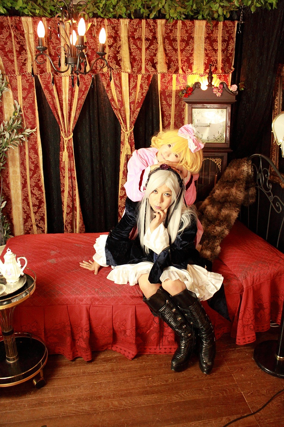 2girls blonde_hair boots couch cup curtains dress hat indoors knee_boots long_hair multiple_cosplay multiple_girls ribbon sitting tagme