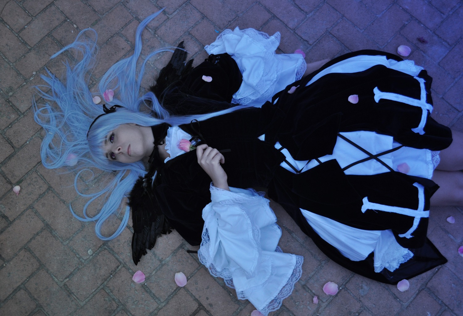 1girl black_dress brick_wall dress feathers floor flower frills from_above long_hair long_sleeves lying on_back on_floor pavement solo stone_floor suigintou tile_floor tiles wooden_floor