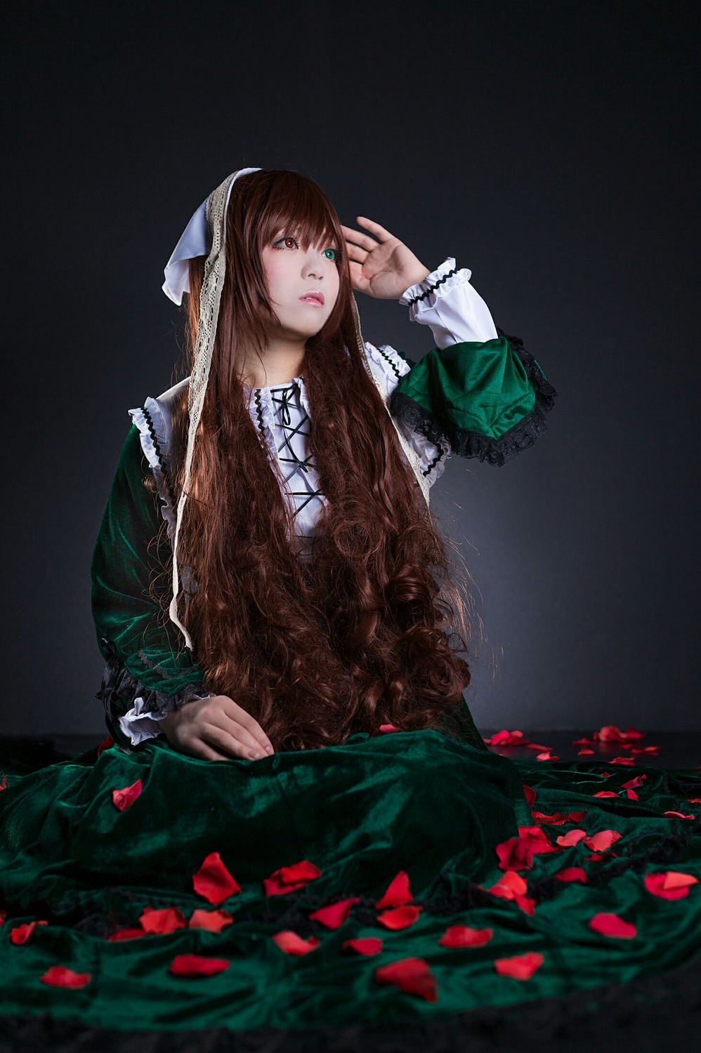 1girl bangs brown_hair dress flower green_dress green_eyes lips long_hair long_sleeves petals sitting solo suiseiseki