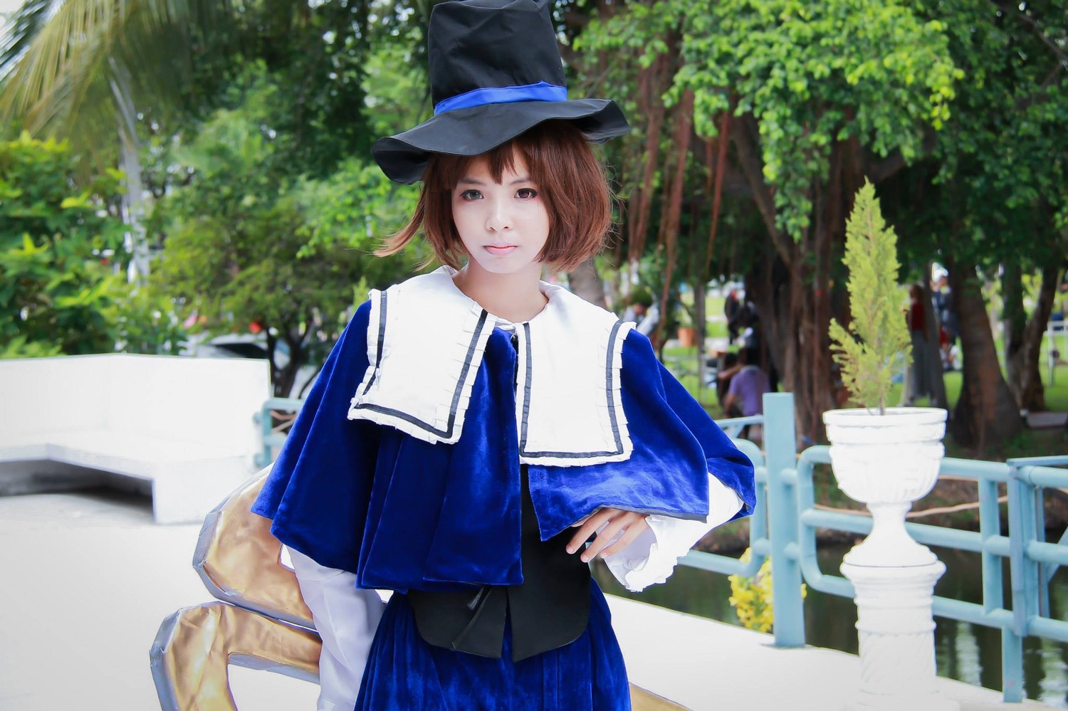 1girl 3d blue_dress blue_headwear blue_skirt blurry brown_eyes brown_hair capelet day hat looking_at_viewer outdoors short_hair skirt solo souseiseki standing tree