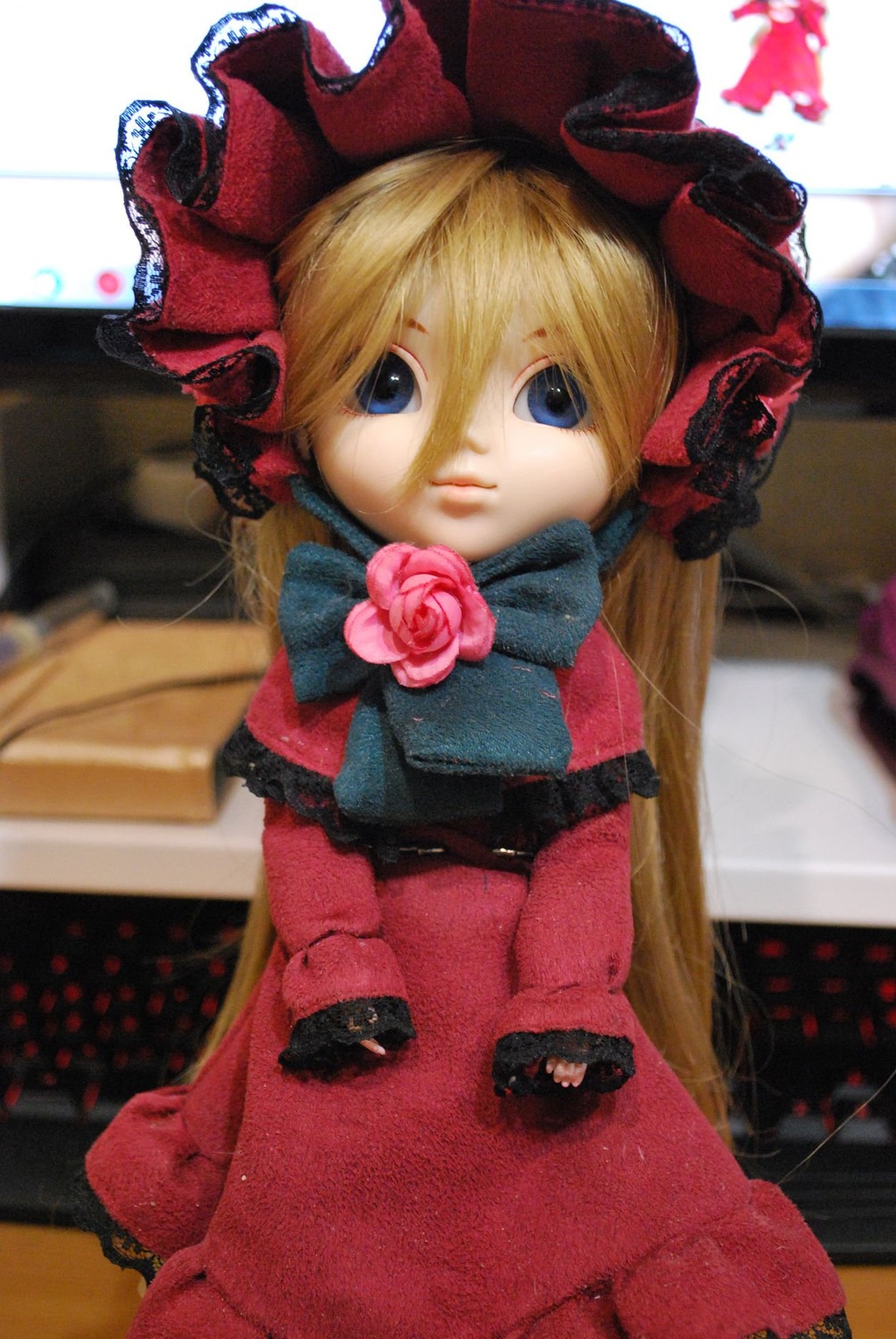 1girl blonde_hair blue_eyes blurry blurry_background bonnet bow depth_of_field doll dress flower long_hair looking_at_viewer photo pink_flower pink_rose red_dress red_flower red_rose rose shinku solo