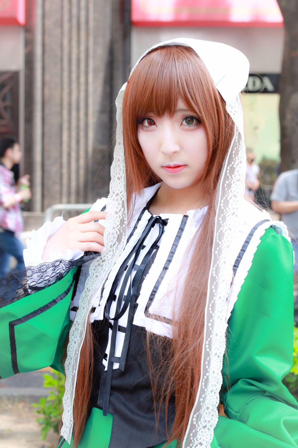 1girl 3d bangs blurry blurry_background blurry_foreground brown_hair depth_of_field dress green_dress green_eyes heterochromia lace lips long_hair long_sleeves looking_at_viewer neck_ribbon photo ribbon solo suiseiseki upper_body