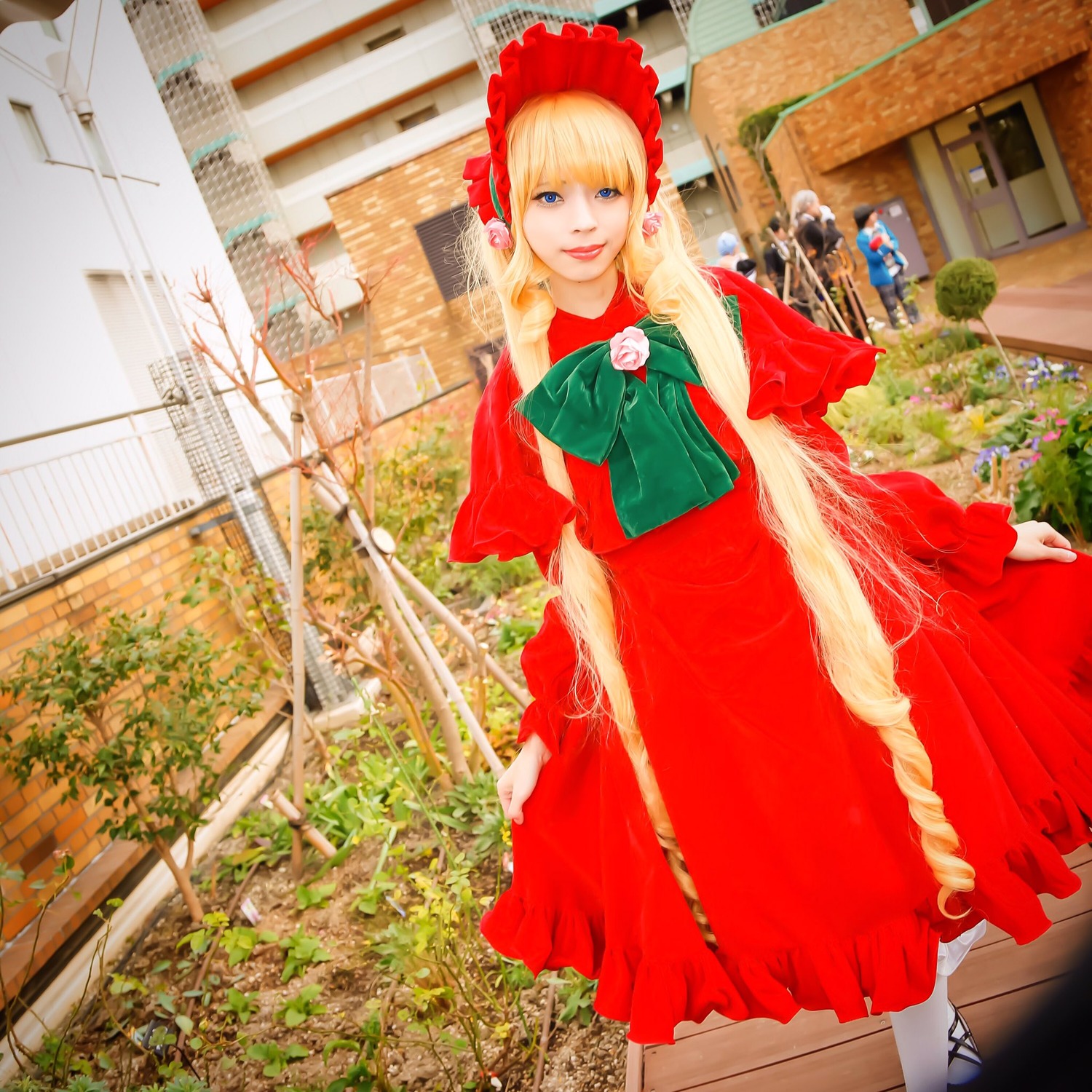 1girl blonde_hair blue_eyes bonnet building capelet dress flower long_hair looking_at_viewer power_lines red_dress shinku smile solo