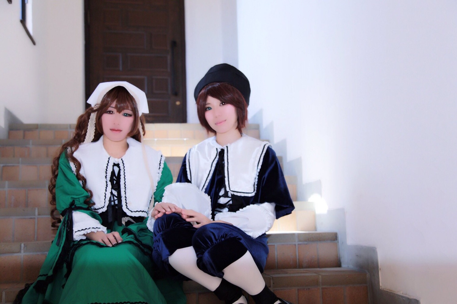 2girls apron bangs blue_eyes brown_hair closed_mouth dress green_dress hat indoors long_sleeves looking_at_viewer multiple_cosplay multiple_girls sisters sitting smile tagme
