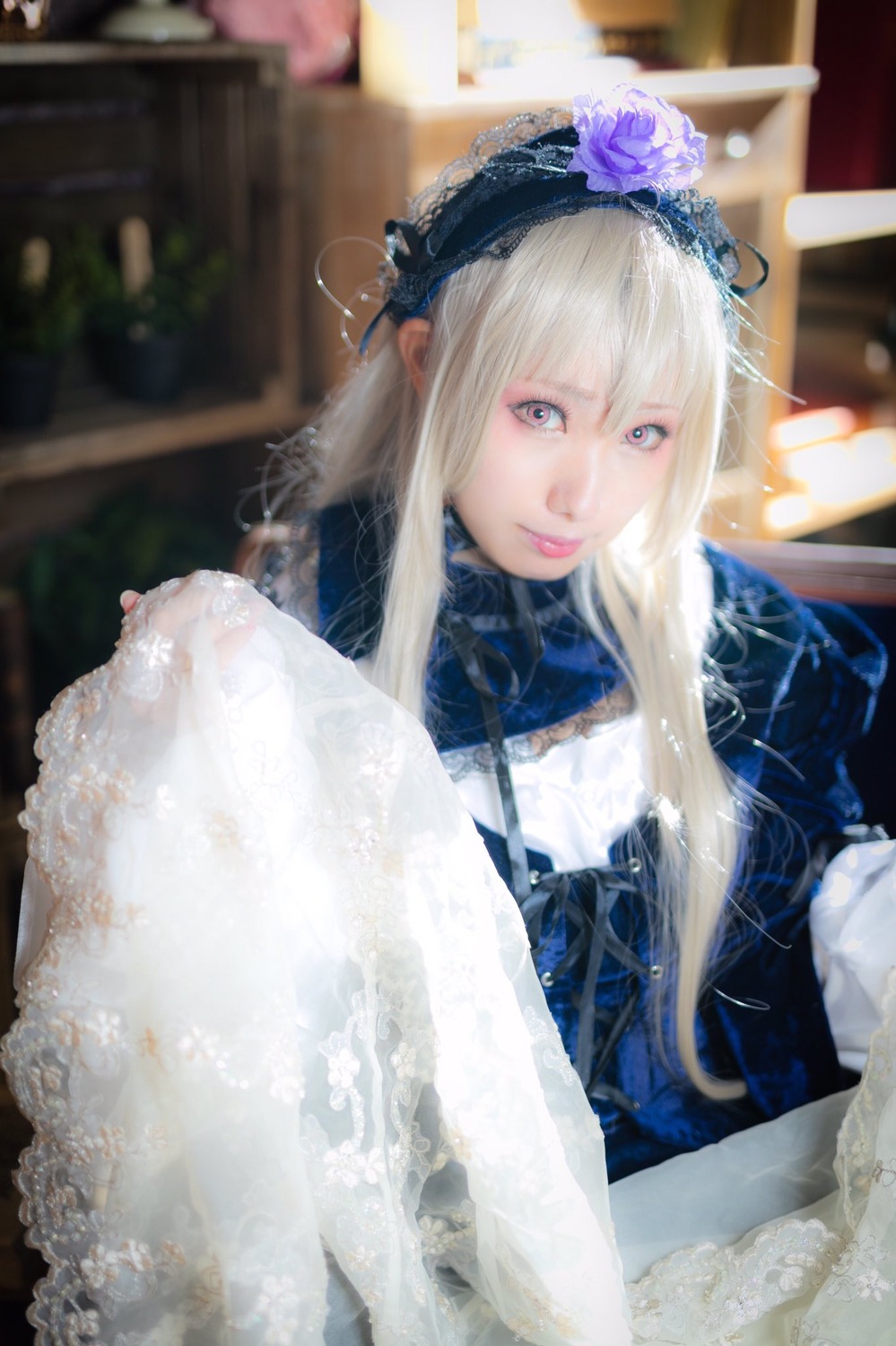 1girl bangs blue_eyes blurry blurry_background closed_mouth depth_of_field dress flower frills hair_flower hair_ornament lips long_hair long_sleeves looking_at_viewer sitting solo suigintou upper_body