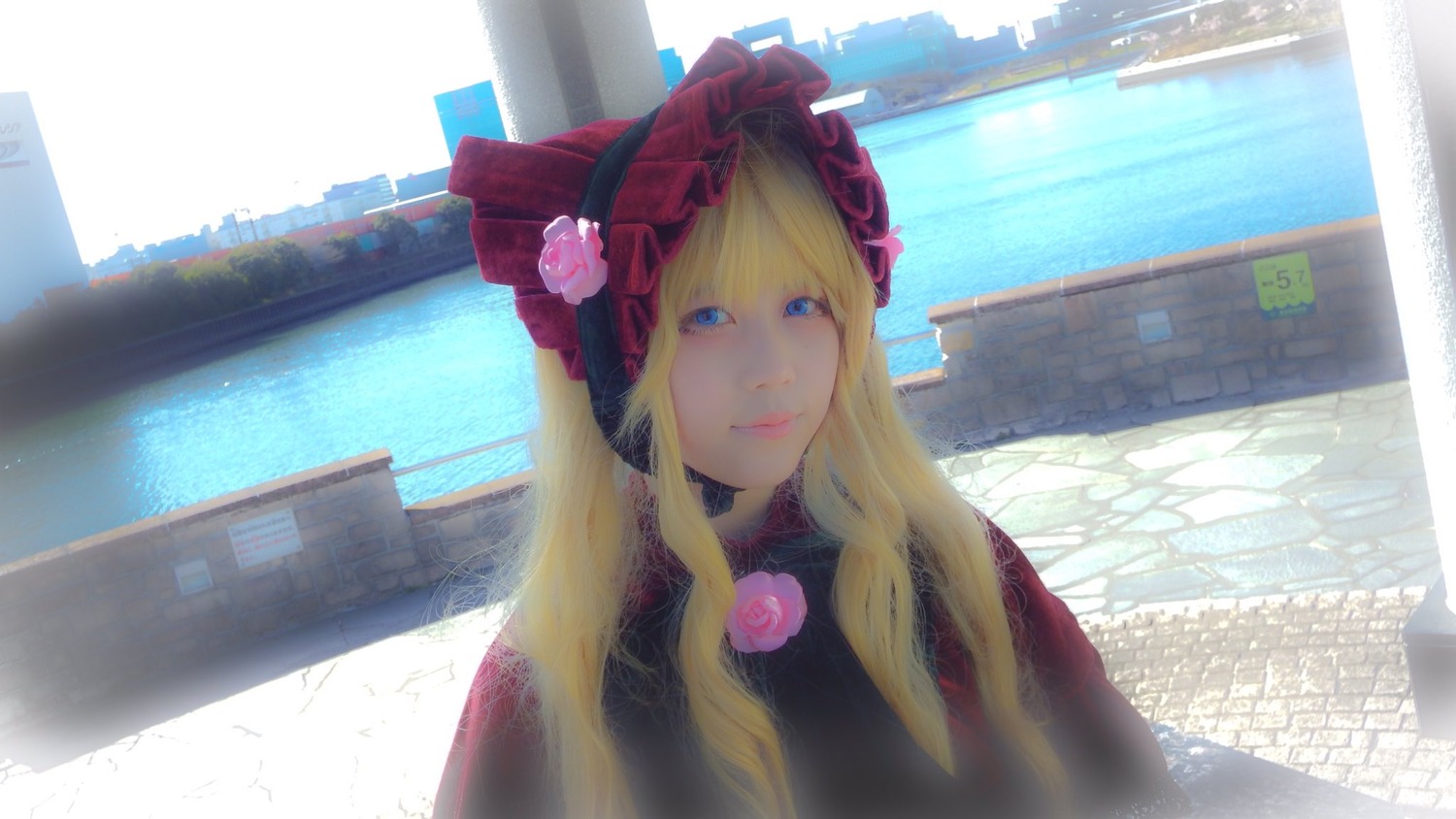 1girl bangs blonde_hair blue_eyes bonnet building city closed_mouth flower long_hair looking_at_viewer pink_flower rose shinku smile solo