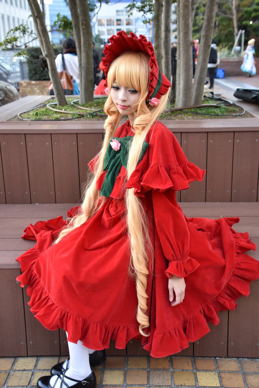 1girl blonde_hair blurry bonnet building depth_of_field dress frills house long_hair long_sleeves outdoors pantyhose pavement red_dress shinku shoes smile solo standing tile_floor tiles white_legwear