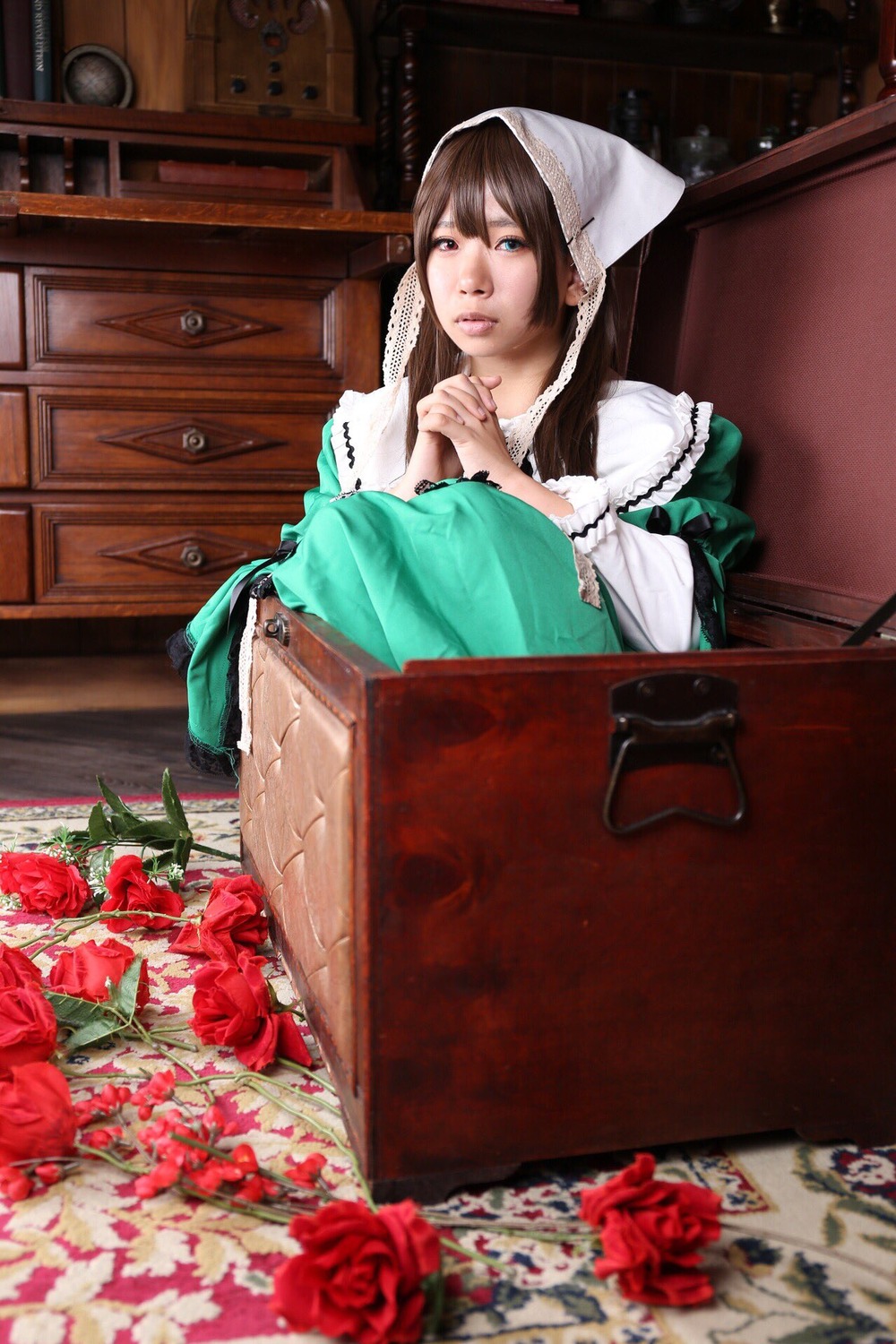 1girl blue_eyes brown_hair dress flower green_dress long_hair red_flower red_rose rose sitting solo suiseiseki vase