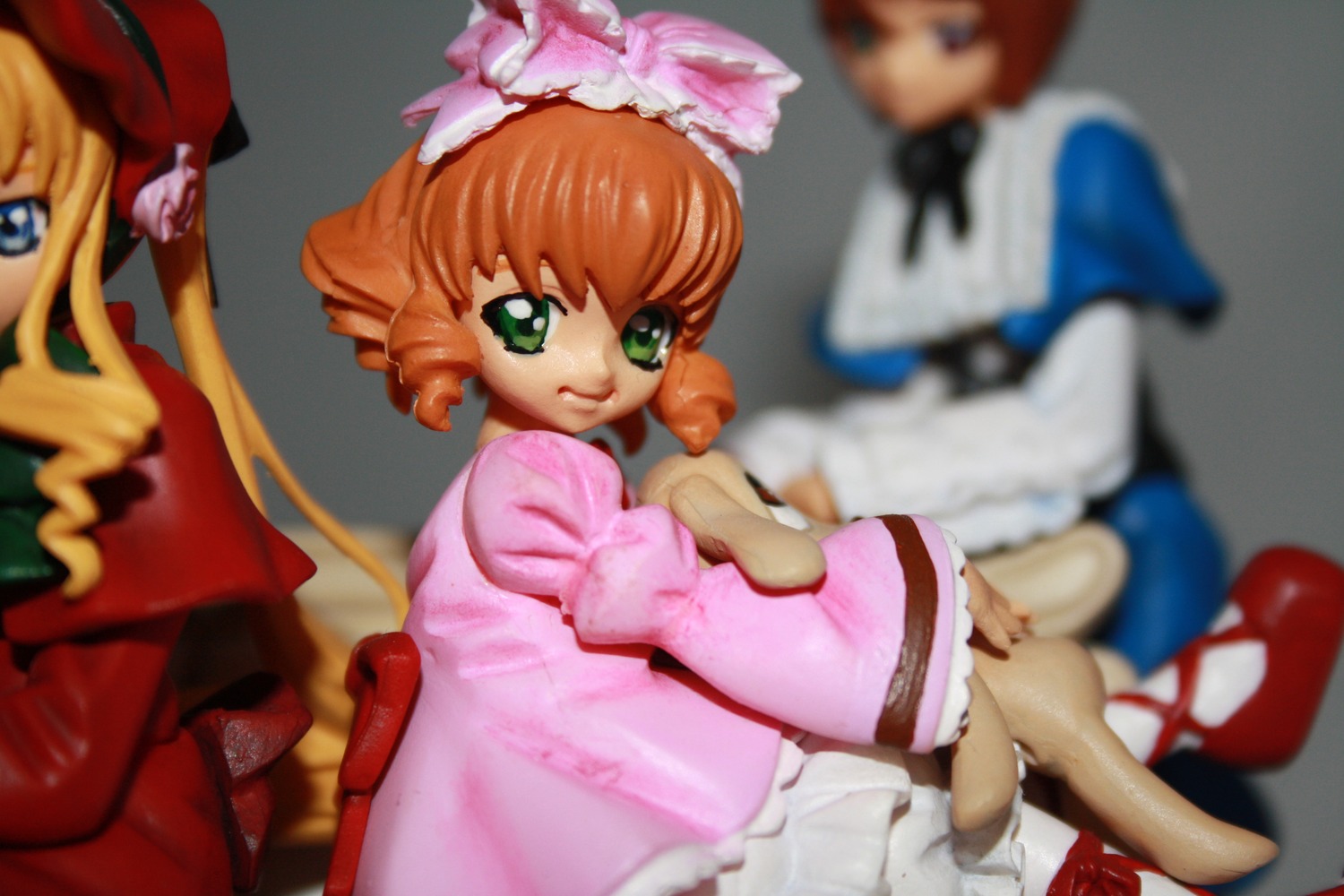 blonde_hair blurry blurry_background blurry_foreground bow depth_of_field doll dress figure green_eyes hat hina_ichigo long_sleeves motion_blur multiple_dolls multiple_girls photo pink_bow pink_dress short_hair tagme