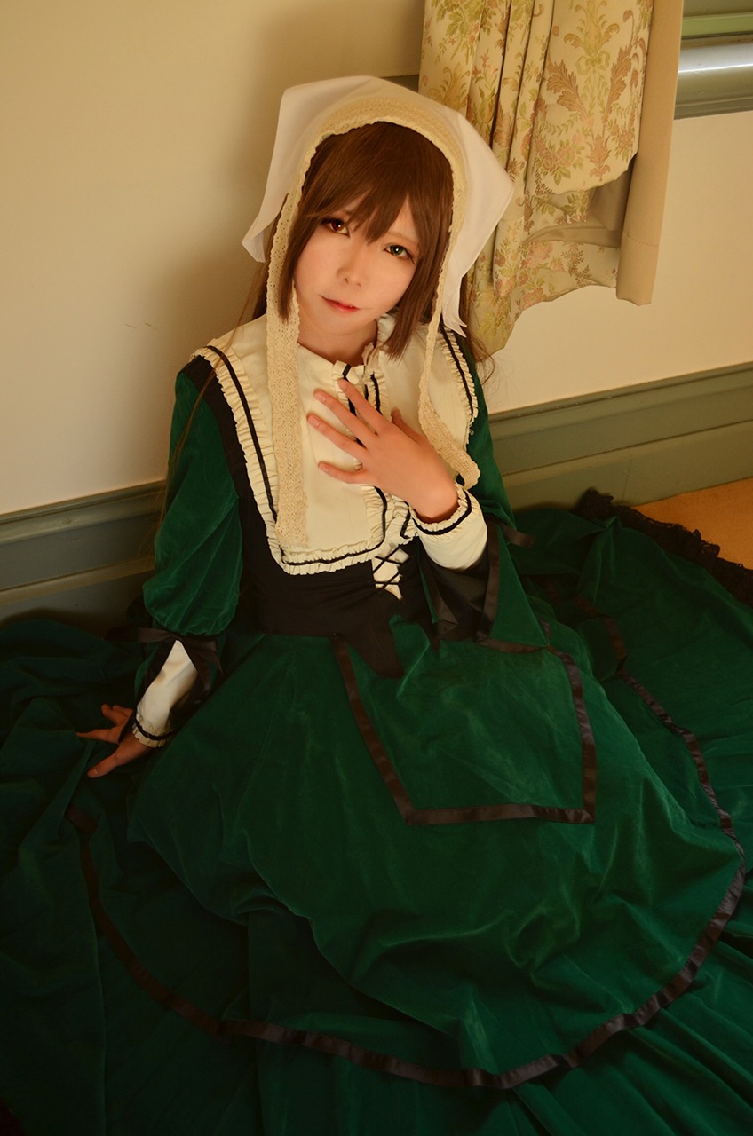 1girl brown_hair dress green_dress green_eyes heterochromia indoors long_sleeves looking_at_viewer sitting smile solo suiseiseki