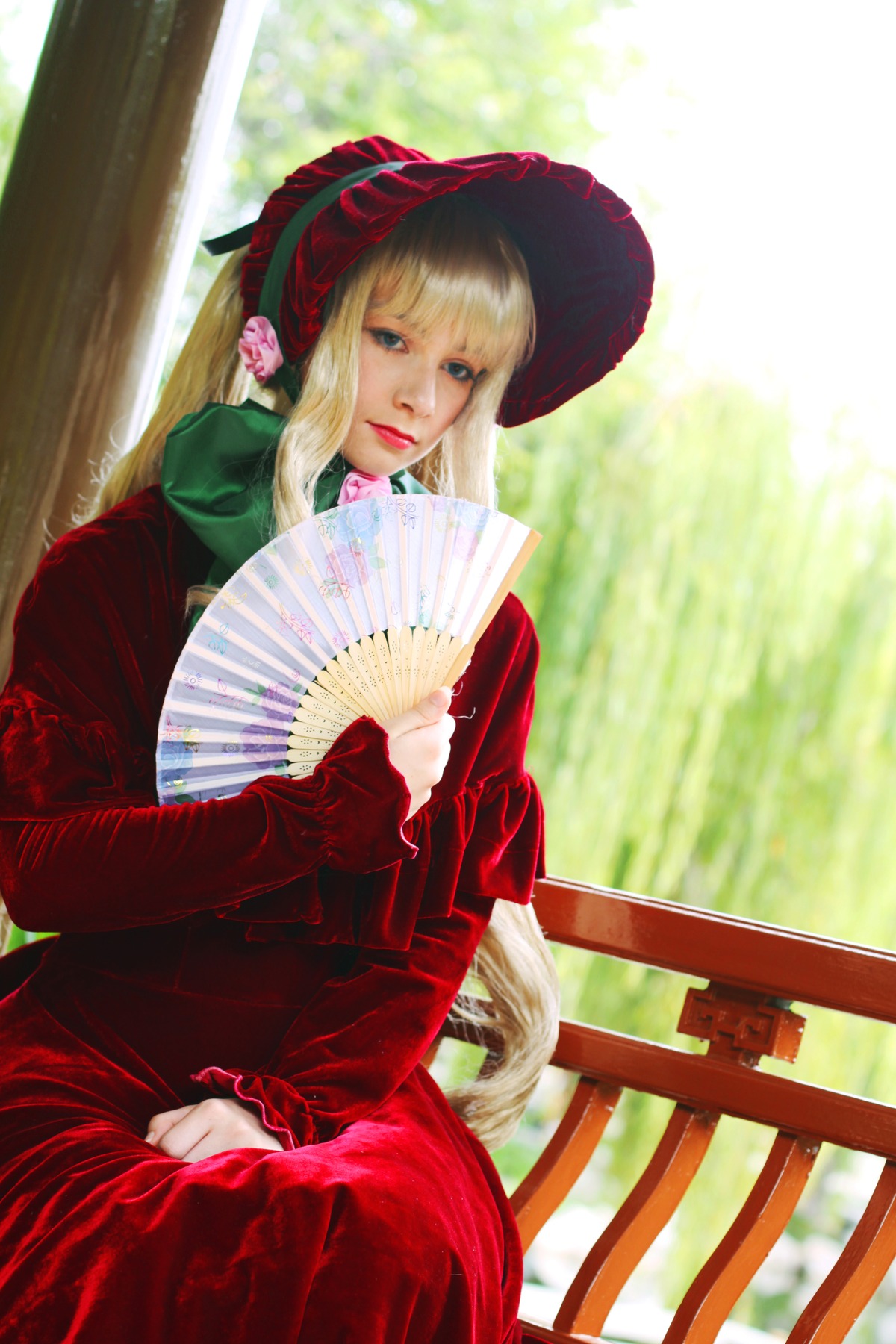 1girl bangs blonde_hair blue_eyes bonnet dress fan flower folding_fan forest hat lips long_hair long_sleeves looking_at_viewer nature red_dress shinku sitting solo sunlight
