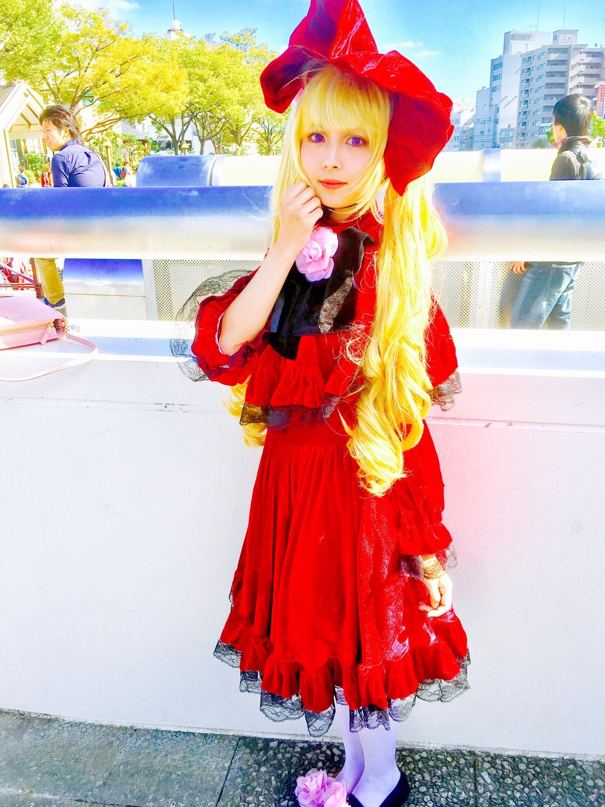 1girl blonde_hair bow building day dress flower hair_bow long_hair looking_at_viewer outdoors purple_eyes red_dress shinku sky smile solo standing tree