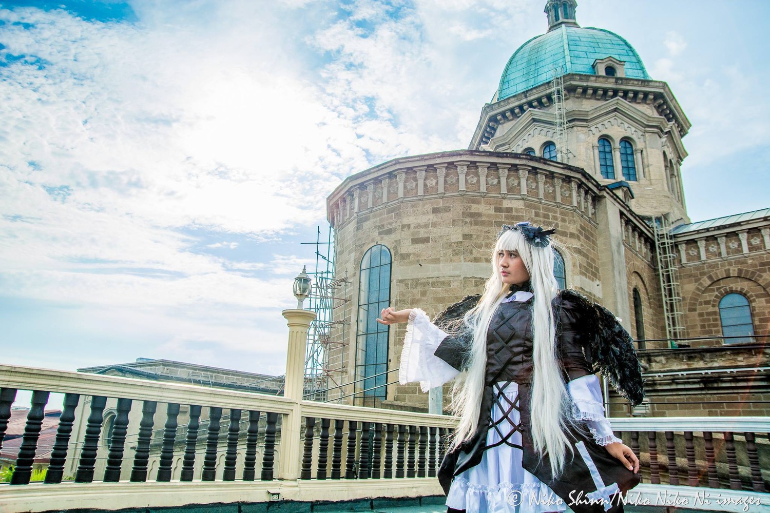 1girl blue_sky building day dress hair_ornament long_hair long_sleeves outdoors railing silver_hair sky solo standing suigintou wings