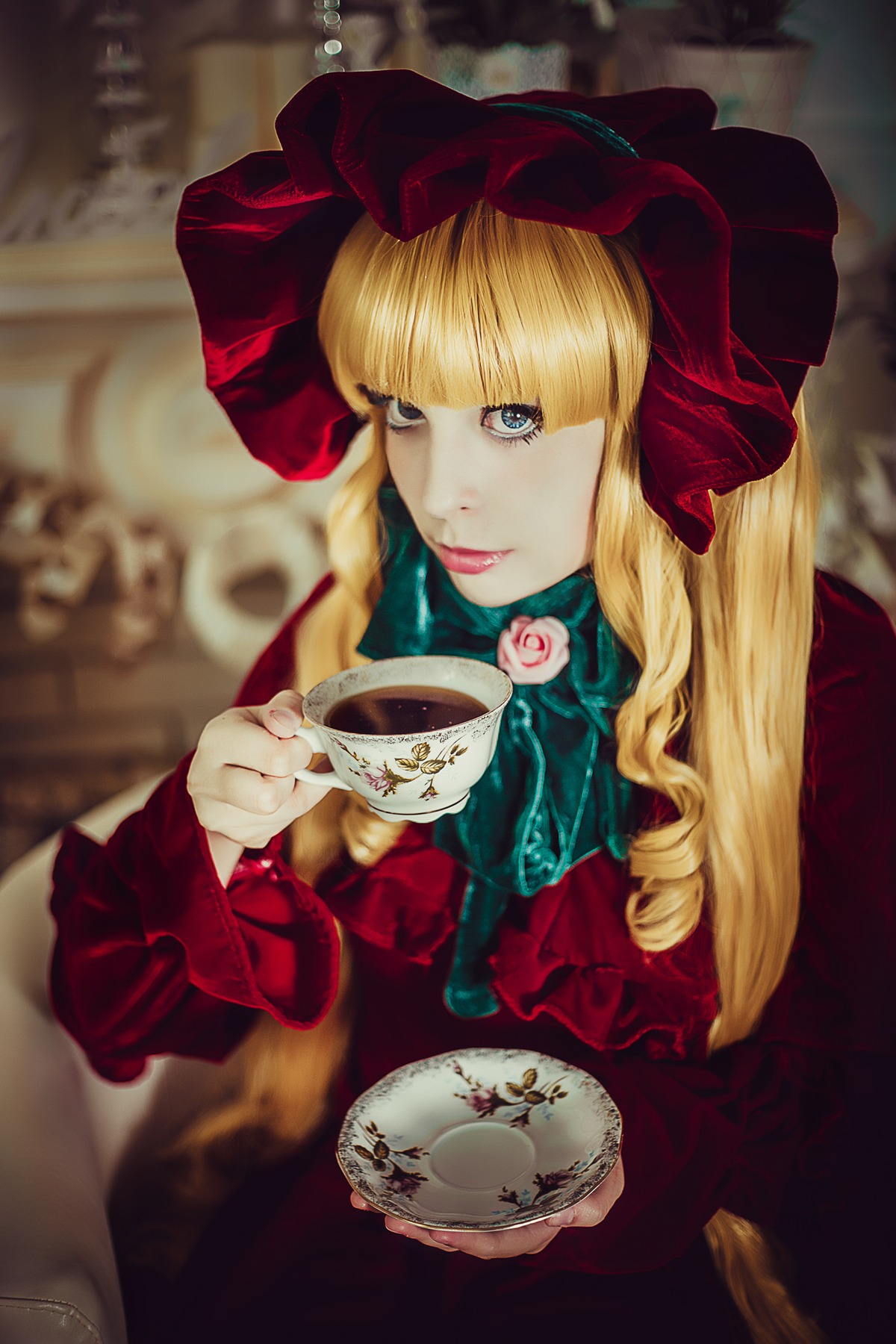 1girl bangs blonde_hair blue_eyes blurry blurry_background bonnet bow cup depth_of_field dress flower lips long_hair looking_at_viewer rose saucer shinku solo tea teacup