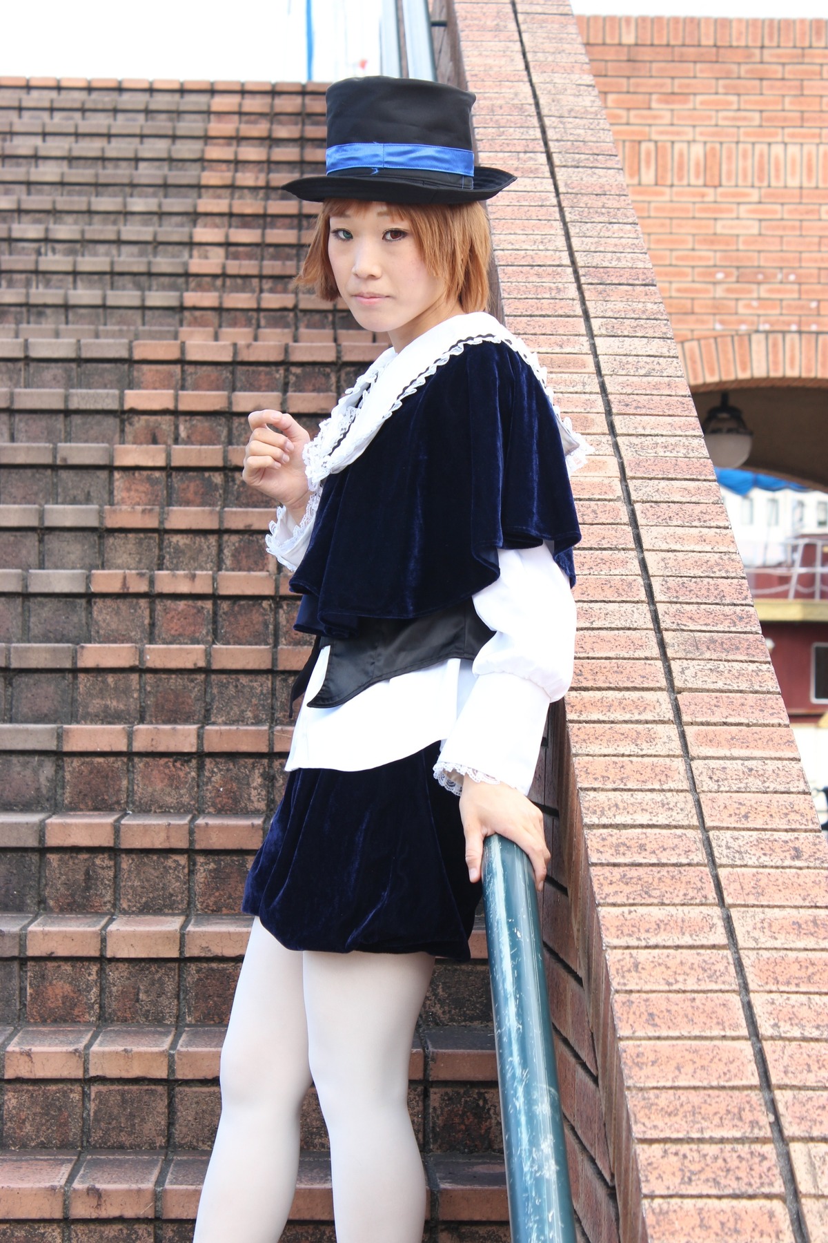 1girl black_skirt blonde_hair blue_eyes brick_wall fence hat long_sleeves looking_at_viewer looking_back outdoors pantyhose railing skirt solo souseiseki standing top_hat white_legwear