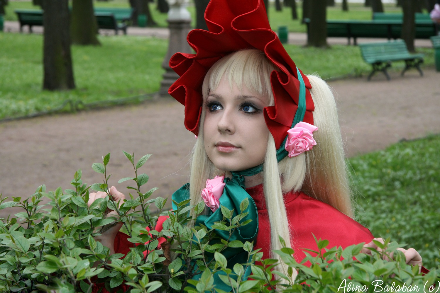 1girl bangs blonde_hair blue_eyes blurry blurry_background bonnet building day depth_of_field flower lips long_hair outdoors photo plant shinku solo watermark