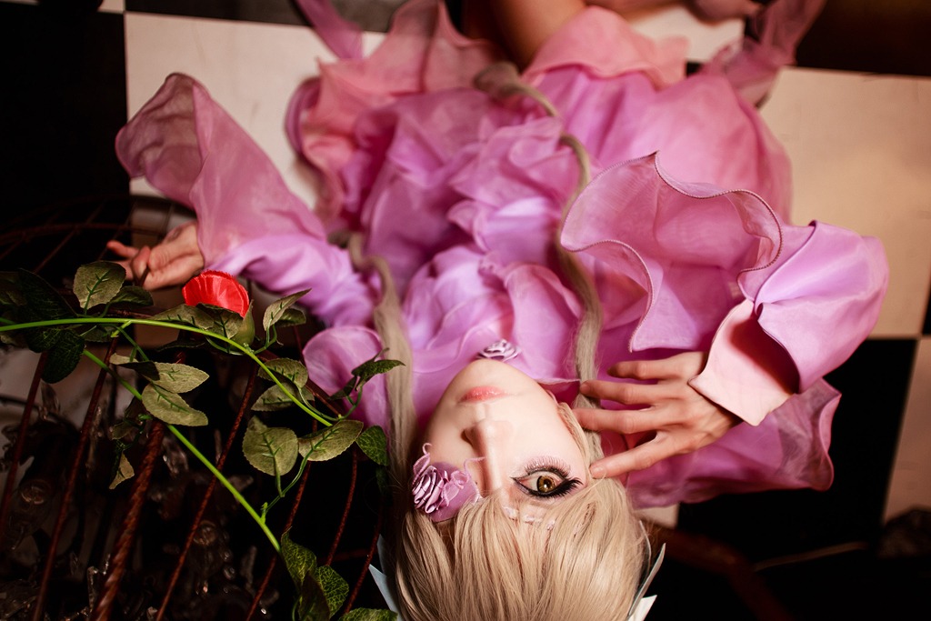 1girl argyle barasuishou blonde_hair brown_eyes checkered checkered_floor d.va_(overwatch) eyepatch facepaint lips long_sleeves looking_at_viewer pink_dress solo