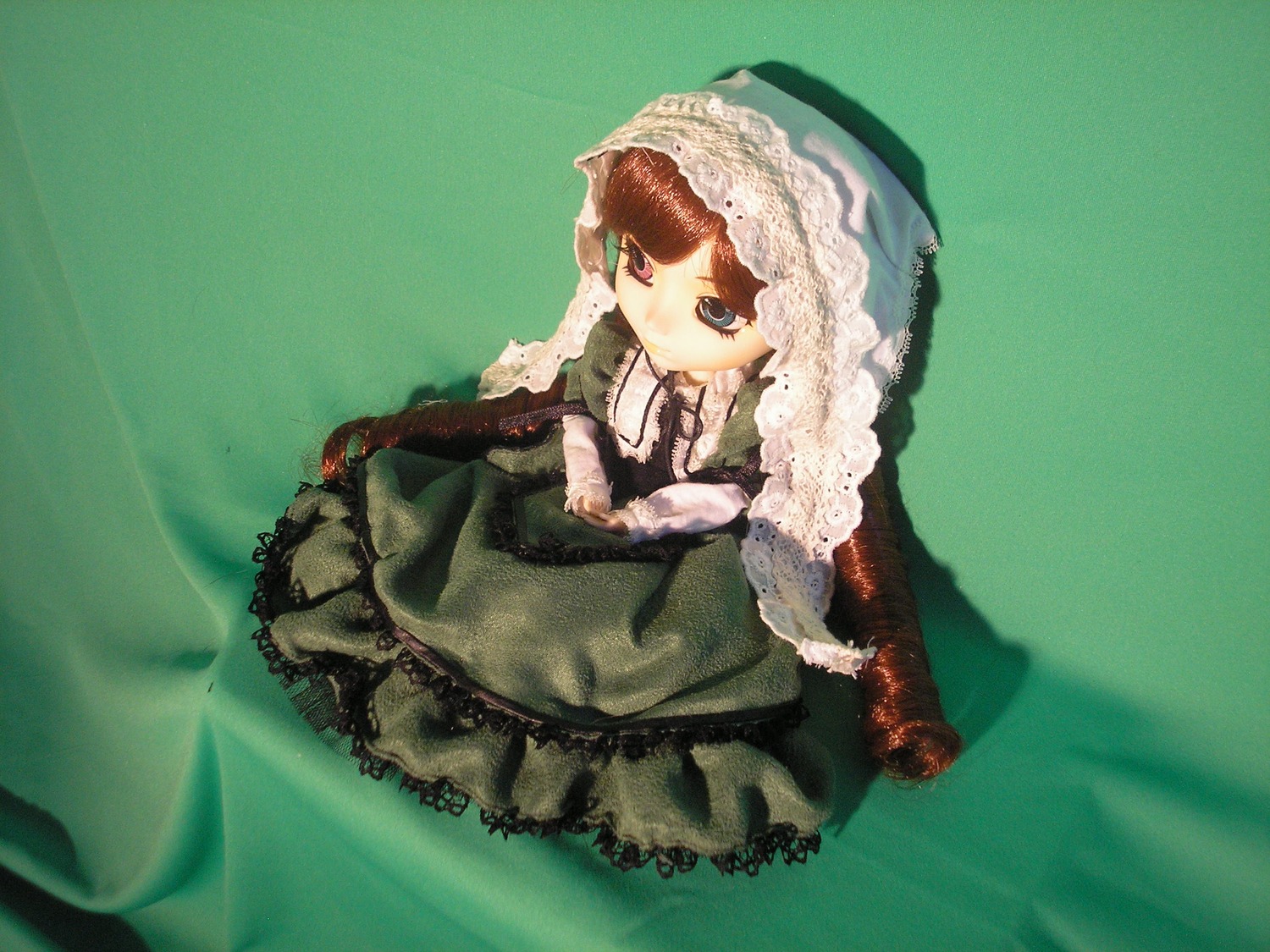 1girl auto_tagged bangs brown_hair doll dress frills green_background green_dress heterochromia lolita_fashion long_hair long_sleeves sitting solo suiseiseki