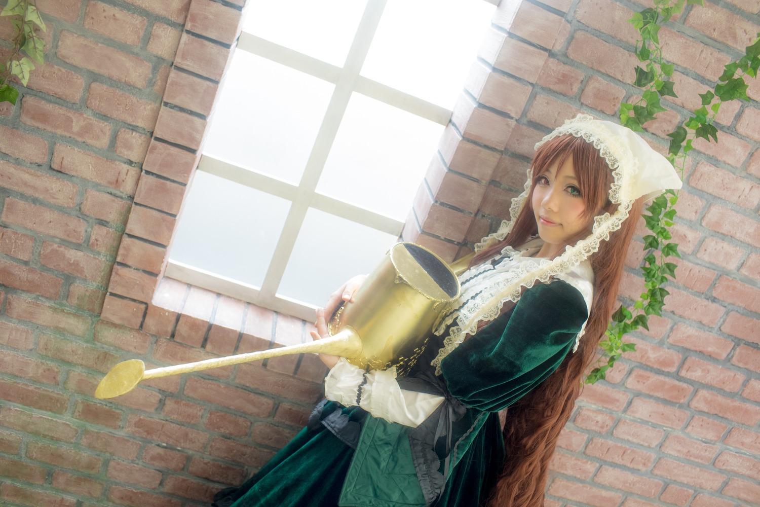 1girl apron brick_wall brown_hair green_dress green_eyes holding long_hair long_sleeves looking_at_viewer smile solo standing suiseiseki wall watering_can window