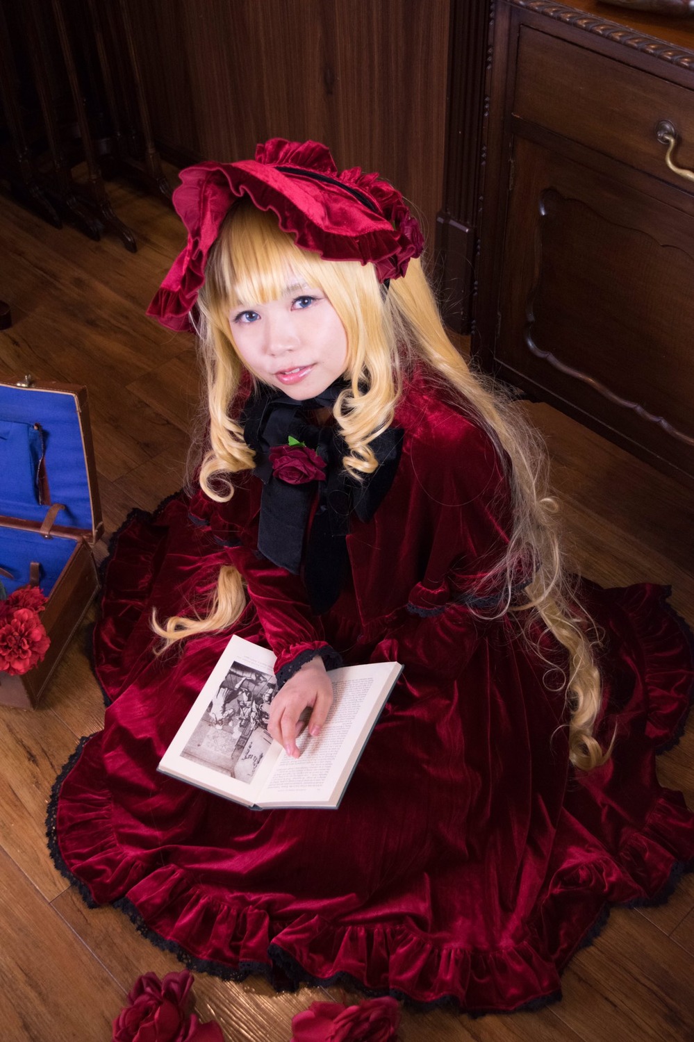 1girl blonde_hair blue_eyes book bow dress flower lips lolita_fashion long_hair looking_at_viewer realistic red_dress red_flower red_rose rose shinku sitting solo