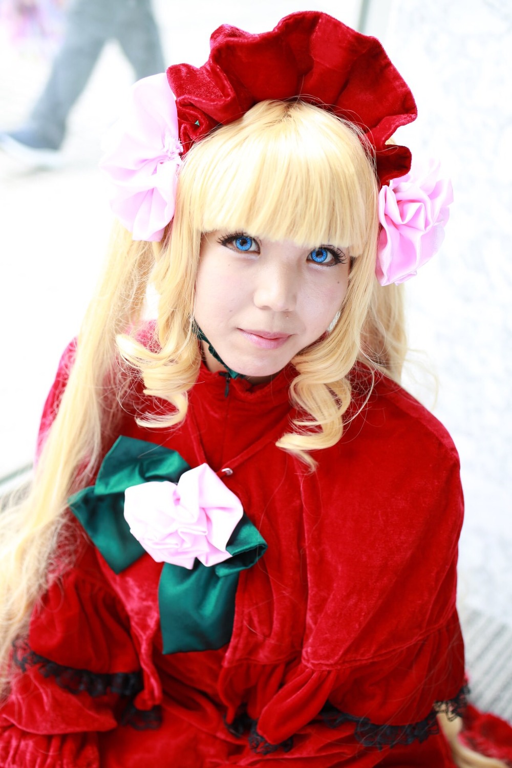 1girl bangs blonde_hair blue_eyes blurry blurry_background bonnet bow depth_of_field dress flower lips long_hair looking_at_viewer red_capelet red_dress rose shinku smile solo