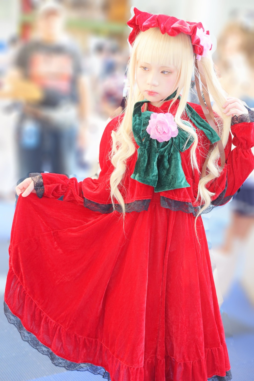 1girl blonde_hair blue_eyes blurry blurry_background blurry_foreground bonnet bow depth_of_field dress flower green_neckwear long_hair long_sleeves looking_at_viewer photo pink_flower pink_rose red_dress rose shinku solo