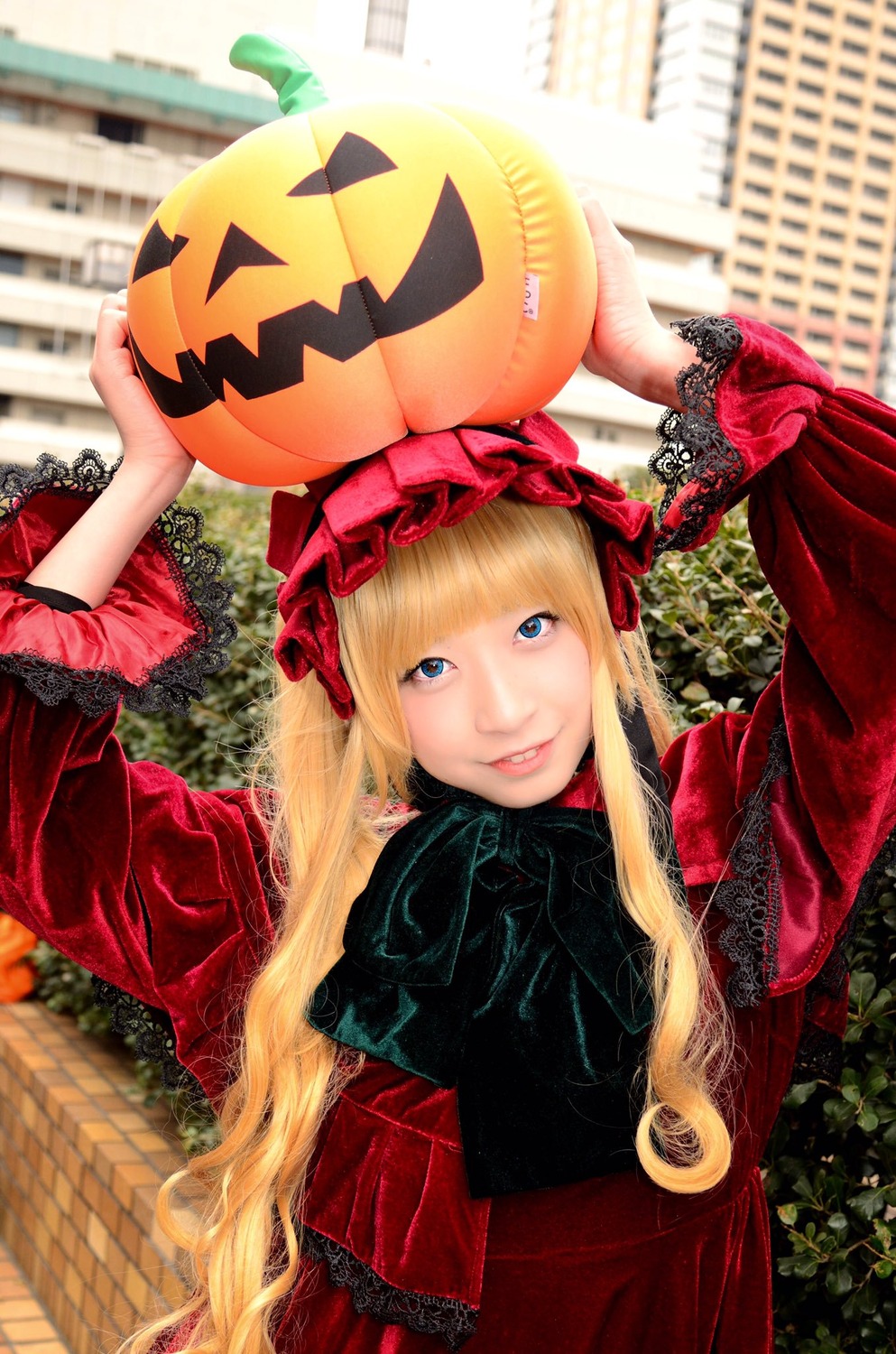 1girl bangs blonde_hair blue_eyes bonnet building dress halloween jack-o'-lantern long_hair looking_at_viewer outdoors pumpkin shinku smile solo