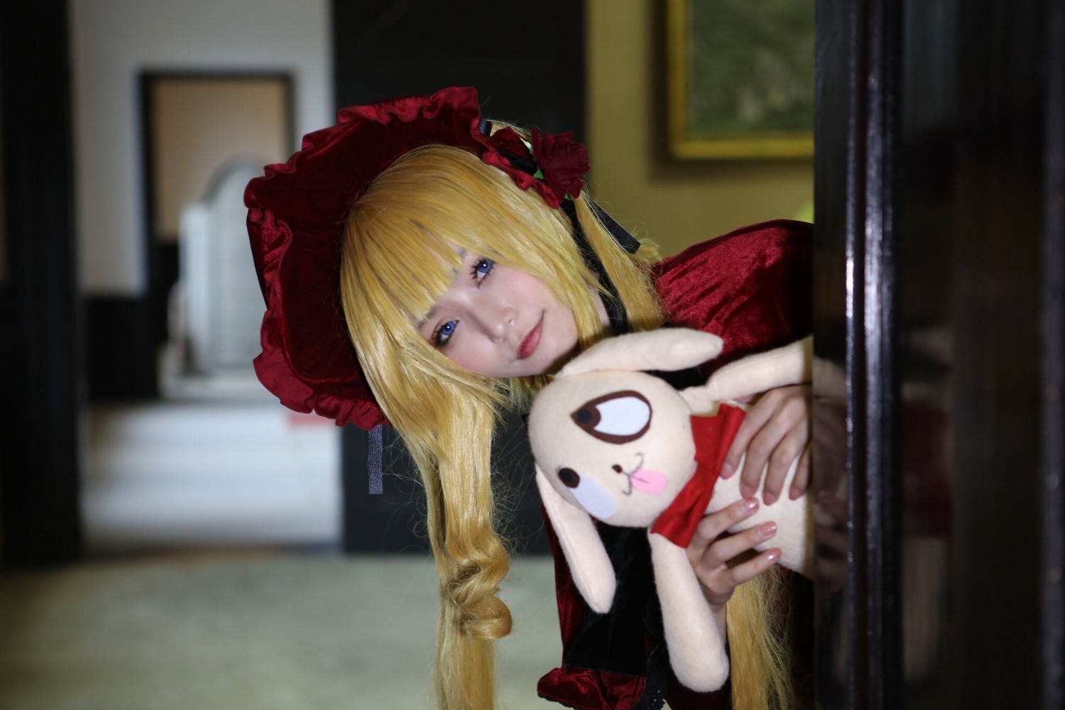 1girl bangs blonde_hair blue_eyes blurry blurry_background blurry_foreground bonnet depth_of_field dress figure indoors long_hair long_sleeves photo realistic shinku solo stuffed_animal