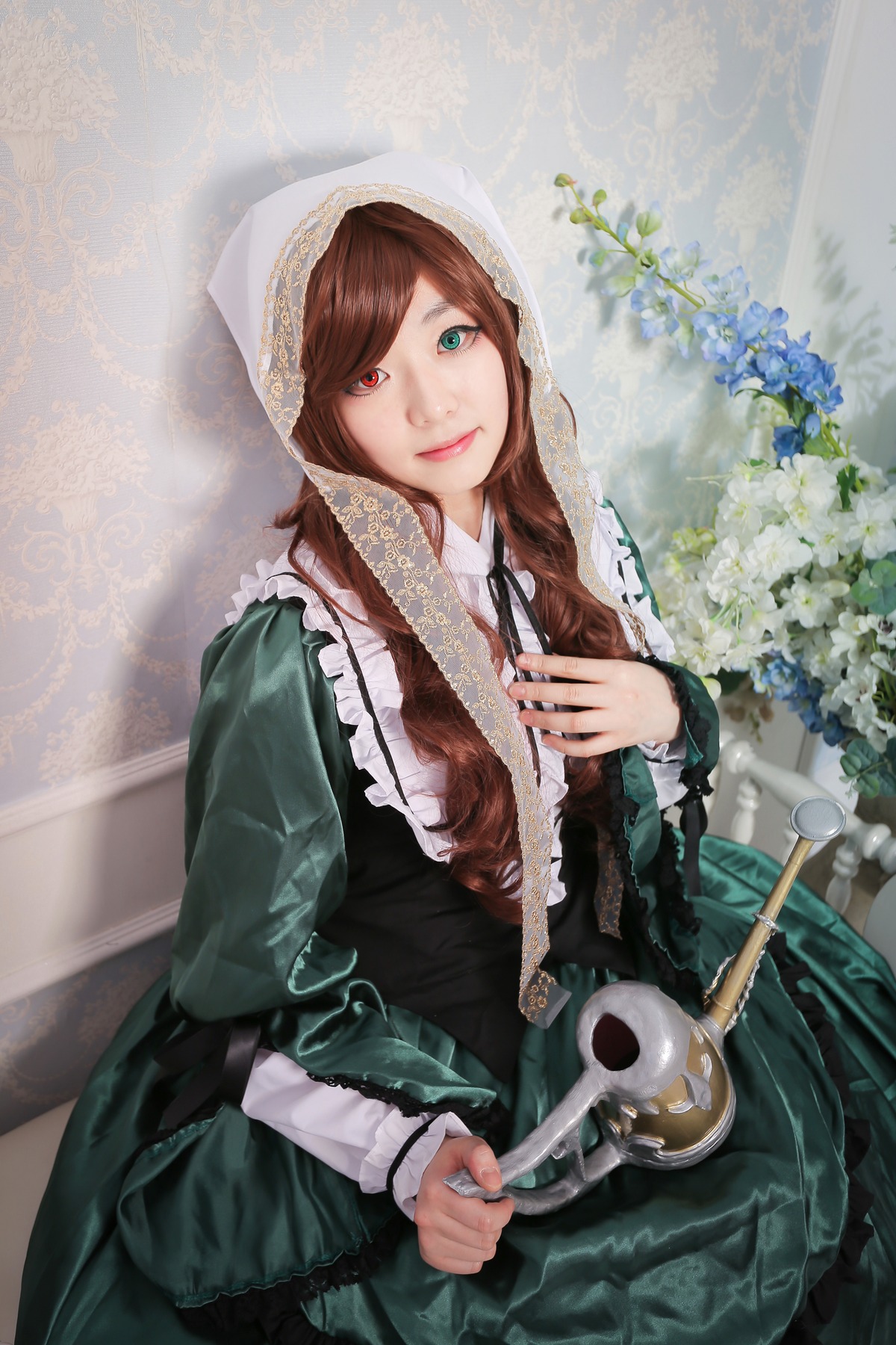 1girl brown_hair dress flower frills green_dress green_eyes heterochromia lips long_hair long_sleeves looking_at_viewer red_eyes smile solo suiseiseki watering_can