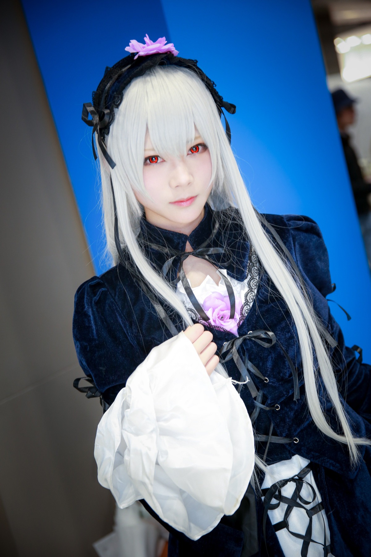 1girl 3d bangs black_ribbon blurry blurry_background closed_mouth depth_of_field dress frills gothic_lolita hairband lips lolita_fashion long_hair long_sleeves looking_at_viewer photo red_eyes ribbon silver_hair solo suigintou